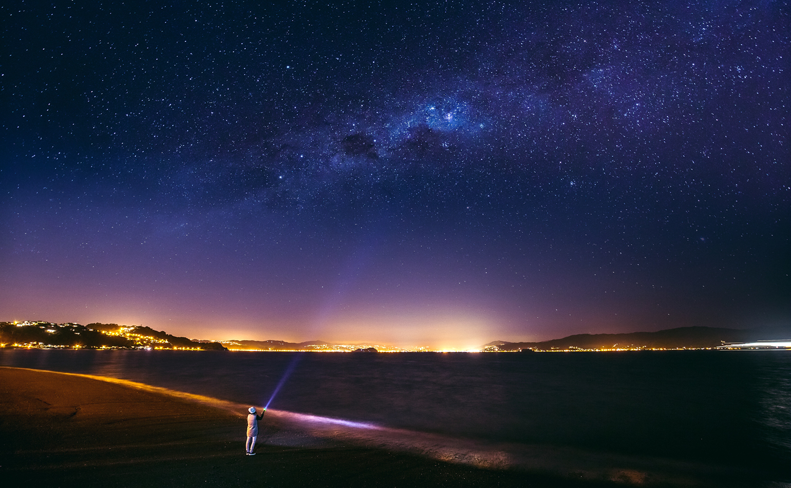 Person shining torch into night sky