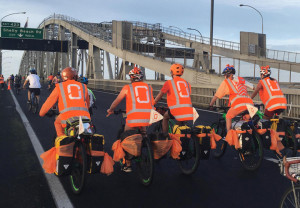 Photo: 5 cyclists are on the Auckland Harbour Bridge. They are wearing High-Vis vests with 0 on the back.