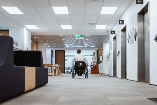 A person in a wheelchair moving towards an escape route in a building marked by an exit sign